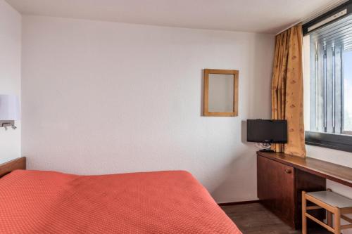 une chambre avec un lit, une télévision et une fenêtre dans l'établissement L'Aiguille - maeva Home - Appartement 2 pièces 5 personnes Confort MAE-2197, à Chamonix-Mont-Blanc