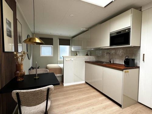 a kitchen with white cabinets and a table with chairs at Studio 43 in Hollum