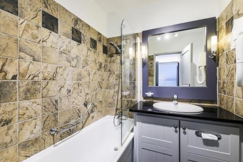une salle de bain avec une baignoire, un lavabo et un miroir dans l'établissement Résidence Les Arcs 1950 Le Village - maeva Home - Appartement 3 pièces 6 personnes - Prestige - super Home MAE-3896, à Bourg-Saint-Maurice