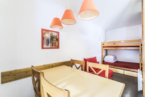 Cette chambre comprend une table et deux lits superposés. dans l'établissement Résidence Les Chalets des Arolles - maeva Home - Studio 5 personnes Confort MAE-6380, à La Plagne Tarentaise