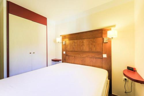 - une chambre avec un lit blanc et une tête de lit en bois dans l'établissement Résidence La Marelle et Le Rami - maeva Home - Appartement 2 pièces 5 personnes Sélection MAE-6258, à La Plagne Tarentaise