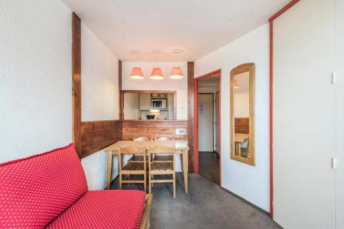 un salon avec une table et un canapé rouge dans l'établissement Résidence Les Fontaines Blanches - maeva Home - Appartement 2 pièces 4 personnes - Confort MAE-7290, à Morzine