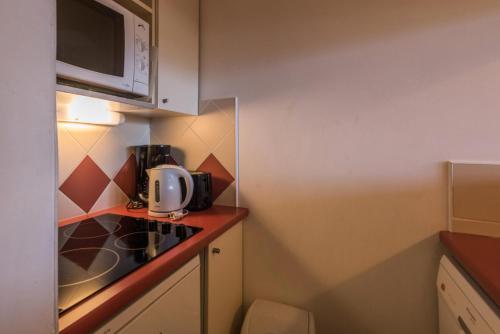 une petite cuisine avec un évier et un micro-ondes dans l'établissement Résidence Les Fontaines Blanches - maeva Home - Appartement 2 pièces 5 personnes Confort MAE-7291, à Avoriaz