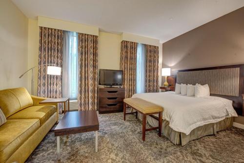 a hotel room with a bed and a couch at Hampton Inn & Suites By Hilton - Rockville Centre in Rockville Centre