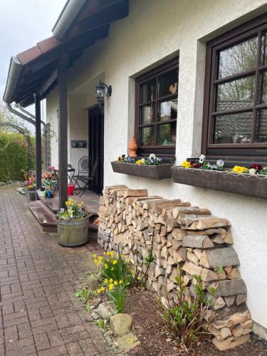 ein Haus mit einer Steinmauer, Fenstern und Blumen in der Unterkunft Ferienwohnung AUSZEIT in Immenhausen