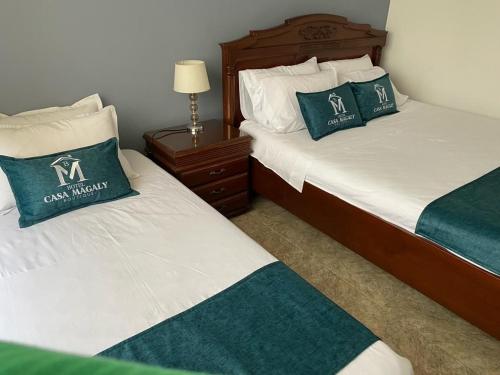 two beds in a hotel room with green and white pillows at Hotel Boutique Casa Magaly in Bogotá