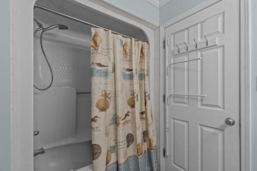 a shower curtain in a bathroom next to a door at Colorful Emerald Isle Home Just Steps to Beach! in Emerald Isle