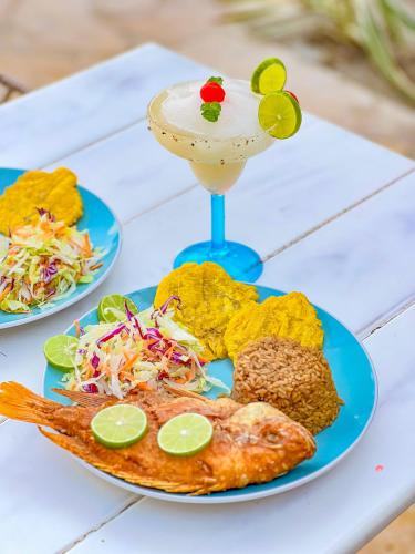 a table with two plates of food and a drink at Hotel Palma Grande by Stanza in Coveñas