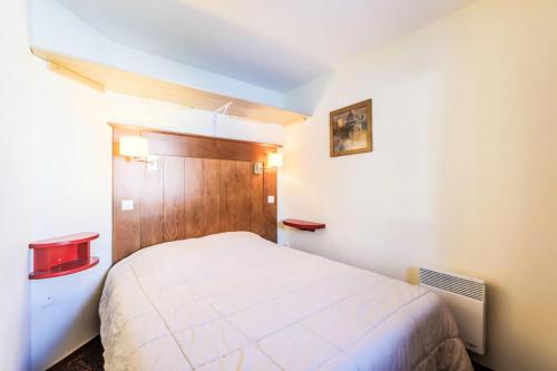 - une chambre avec un lit blanc et une tête de lit en bois dans l'établissement Résidence Le Mont Soleil - maeva Home - Appartement 2 pièces 5 personnes - Sélection MAE-0302, à Mâcot La Plagne