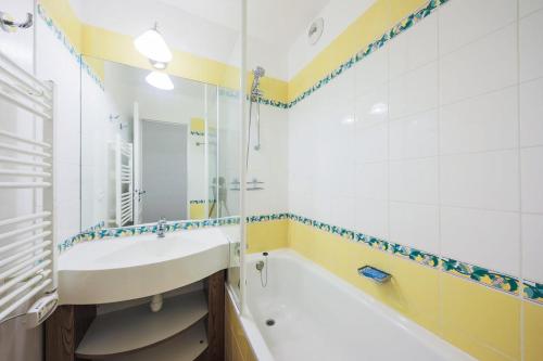 une salle de bain avec un lavabo, une baignoire et un miroir dans l'établissement Résidence Le Thabor - maeva Home - Appartement 2 Pièces 5 Personnes - Confort MAE-0345, à Le Désert