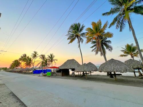 a street with straw umbrellas and palm trees on a beach at Hotel Palma Grande by Stanza in Coveñas