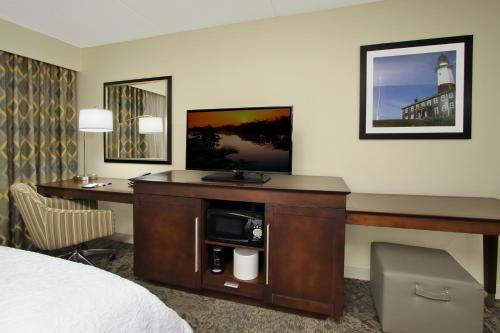 a hotel room with a bed and a desk with a tv at Hampton Inn & Suites By Hilton - Rockville Centre in Rockville Centre