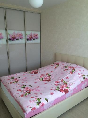 Apartment on Leningradskaya 63 في خاباروفسكي: غرفة نوم بها سرير وردي عليه زهور
