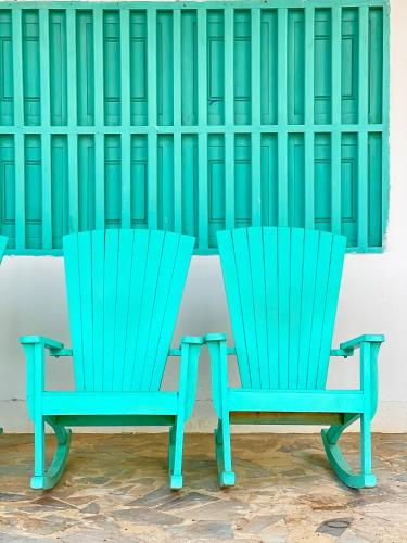 two green chairs sitting in front of a wall at Hotel Palma Grande by Stanza in Coveñas