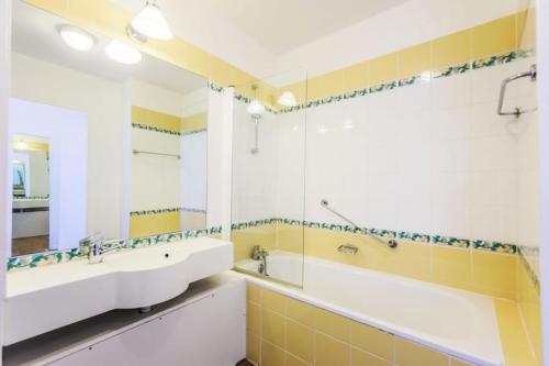 La salle de bains est pourvue de 2 lavabos, d'une baignoire et d'un miroir. dans l'établissement Résidence Le Thabor - maeva Home - Appartement 2 Pièces 4 Personnes - Confo 34, à Le Désert