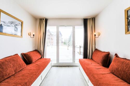 Elle comprend un salon doté d'un mobilier rouge et d'une grande fenêtre. dans l'établissement Résidence Le Thabor - maeva Home - Appartement 2 pièces 5 personnes Confort MAE-2491, à Le Désert