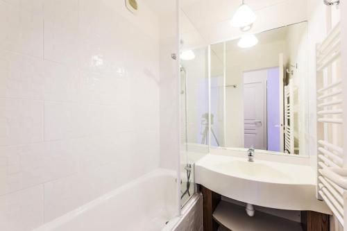 La salle de bains blanche est pourvue d'un lavabo, d'une baignoire et d'un miroir. dans l'établissement Résidence Le Thabor - maeva Home - Appartement 2 pièces 5 personnes Confort MAE-2491, à Le Désert