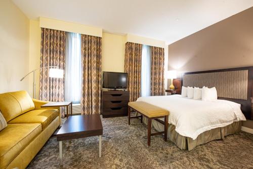 a hotel room with a bed and a couch at Hampton Inn & Suites By Hilton - Rockville Centre in Rockville Centre