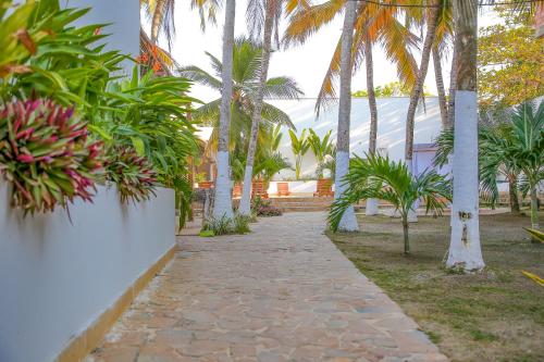a walkway with palm trees and a building at Hotel Palma Grande by Stanza in Coveñas