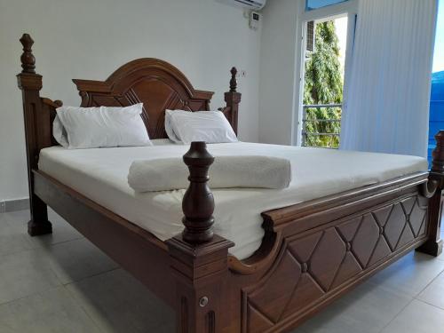un grande letto in legno con lenzuola e cuscini bianchi di Glo stays a Mombasa