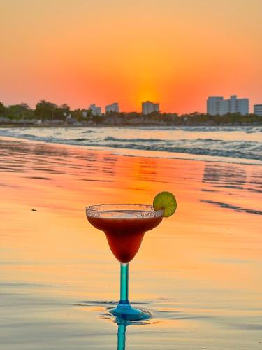 a cocktail with a lime on the beach at sunset at Hotel Palma Grande by Stanza in Coveñas
