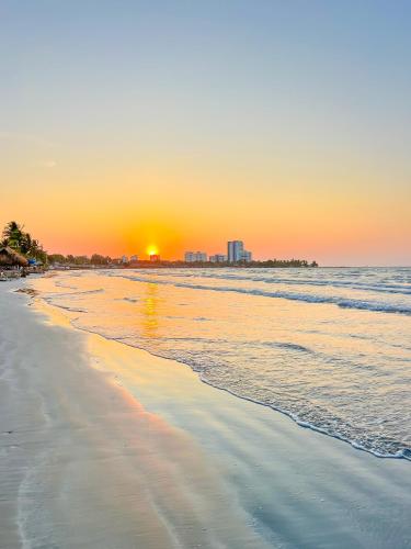 a beach with the sun setting in the distance at Hotel Palma Grande by Stanza in Coveñas