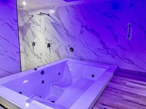 baño con una gran bañera blanca con iluminación púrpura en Cassino Motel 5, en Santo André