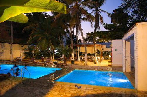 a swimming pool in front of a house at Hotel Palma Grande by Stanza in Coveñas