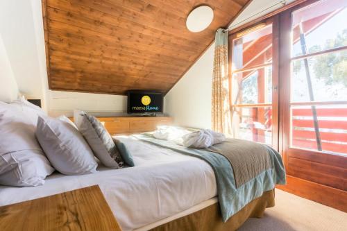 a bedroom with a large bed with a large window at Résidence Les Arcs Le Village - maeva Home - Appartement Pièces Pers. Prest 90 in Bourg-Saint-Maurice