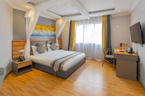 a bedroom with a bed and a desk and a television at Raha Hotel & Suites in Nairobi