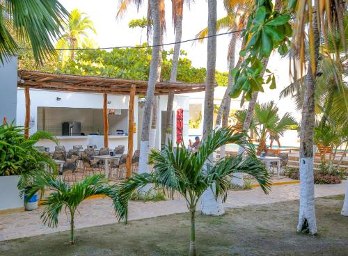 a resort with palm trees and tables and chairs at Hotel Palma Grande by Stanza in Coveñas