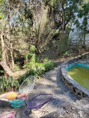 a patio with two chairs and a pool of water at Glamping Cabaña de Granja El Sol Teques y Naturaleza in Xoxocotla