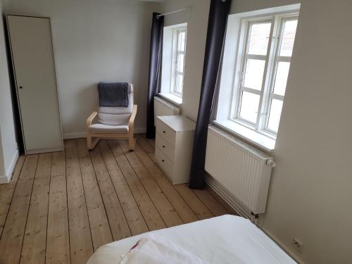 sypialnia z krzesłem i oknem w obiekcie Skrædderens hus w mieście Assens