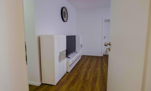 a living room with a television and a white wall at Waldblick am Ring in Kelberg