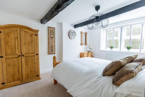 a bedroom with a white bed and a wooden cabinet at FORD GATE - Modern Luxury Cottage based in Holmfirth in Holmfirth