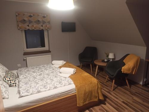 a bedroom with a bed and two chairs and a table at Dom na Klonowym Wzgórzu in Stronie Śląskie
