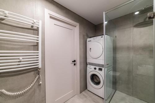 baño con lavadora y secadora de ropa y puerta de cristal en Frida Elite Apartments en Šiauliai