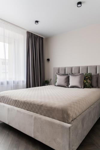 a large bed in a bedroom with a large bed sidx sidx sidx at Frida Elite Apartments in Šiauliai