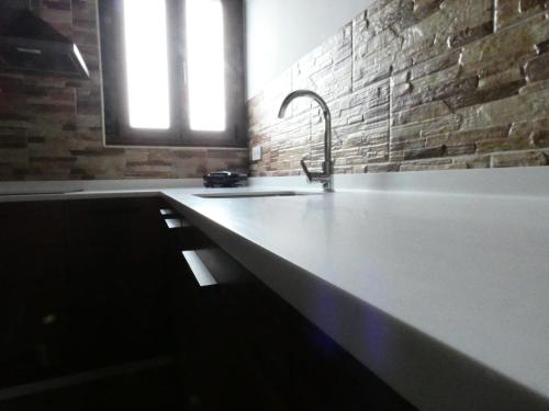 a kitchen with a sink and a brick wall at EL RINCÓN DE DENVER in Suances