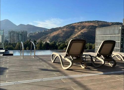 two chairs sitting on a patio near a body of water at Estudio en Estoril cercano a principales centros de ski in Santiago