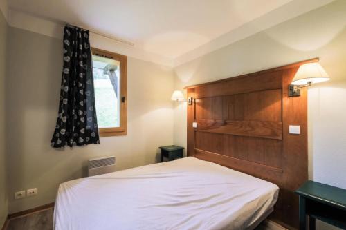- une chambre avec un lit blanc et une tête de lit en bois dans l'établissement Résidence La Marelle et Le Rami - maeva Home - Appartement 2 Pièces 5 Personnes - Sélection MAE-7484, à La Plagne Tarentaise