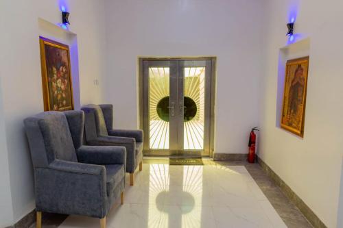 Habitación con 2 sillas y puerta con espejo. en Yona Resort Inn en Ijebu Ode