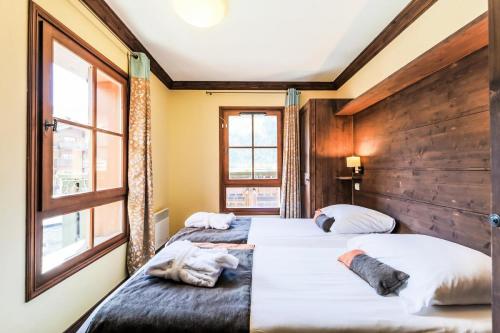 deux lits dans une chambre avec deux fenêtres dans l'établissement Résidence Les Arcs 1950 Le Village - maeva Home - Appartement 3 Pièces 6 Personnes - Sélection MAE-2357, à Bourg-Saint-Maurice