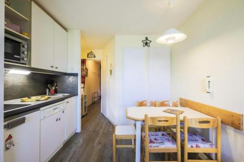 une cuisine avec une table et des chaises dans une pièce dans l'établissement Résidence Le Sextant - maeva Home - Studio 4 Personnes - Confort MAE-7964, à La Plagne Tarentaise