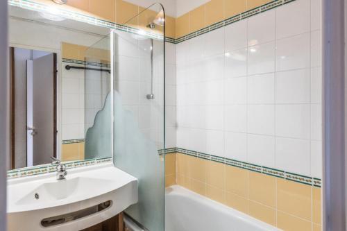 Un baño con lavabo, bañera y espejo. en Résidence Quartier Falaise - maeva Home - Studio 4 personnes Confort MAE-9083, en Avoriaz