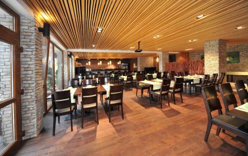 a restaurant with wooden ceilings and tables and chairs at Via Jasna Wellness Apartments in Liptovský Mikuláš