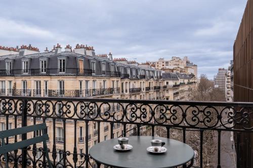 une table sur un balcon avec vue sur les bâtiments dans l'établissement Appartement Guersant - Welkeys, à Paris