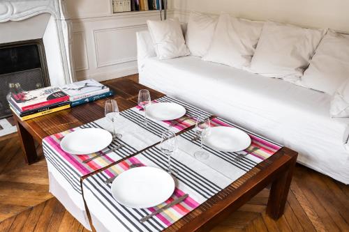 un salon avec une table et un canapé blanc dans l'établissement Appartement Guersant - Welkeys, à Paris
