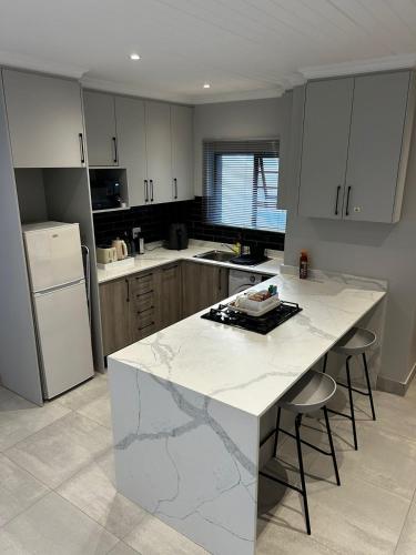 uma cozinha com um balcão branco e um frigorífico branco em Affordable Luxury Apartment em Gqeberha