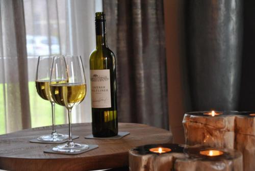 a bottle of wine and two glasses on a table at Prachtige vakantievilla Burdaard in Burdaard